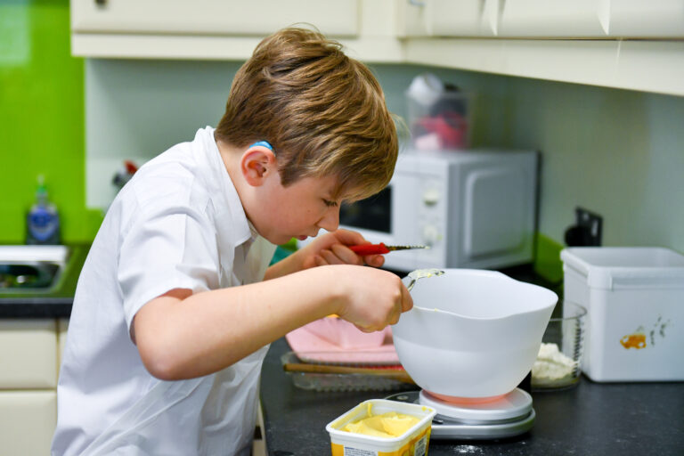 Student in the ILS kitchen weighing out ingredients on talking scales