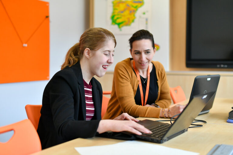 Student and teacher looking at work on a laptop.