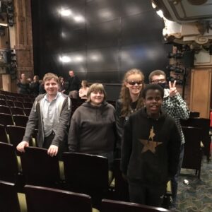 Another view of students in the theatre, all smiles looking at the camera