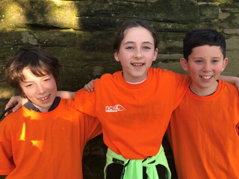 image of the three children. They are wearing orange NCW t shirts and smiling at the camera