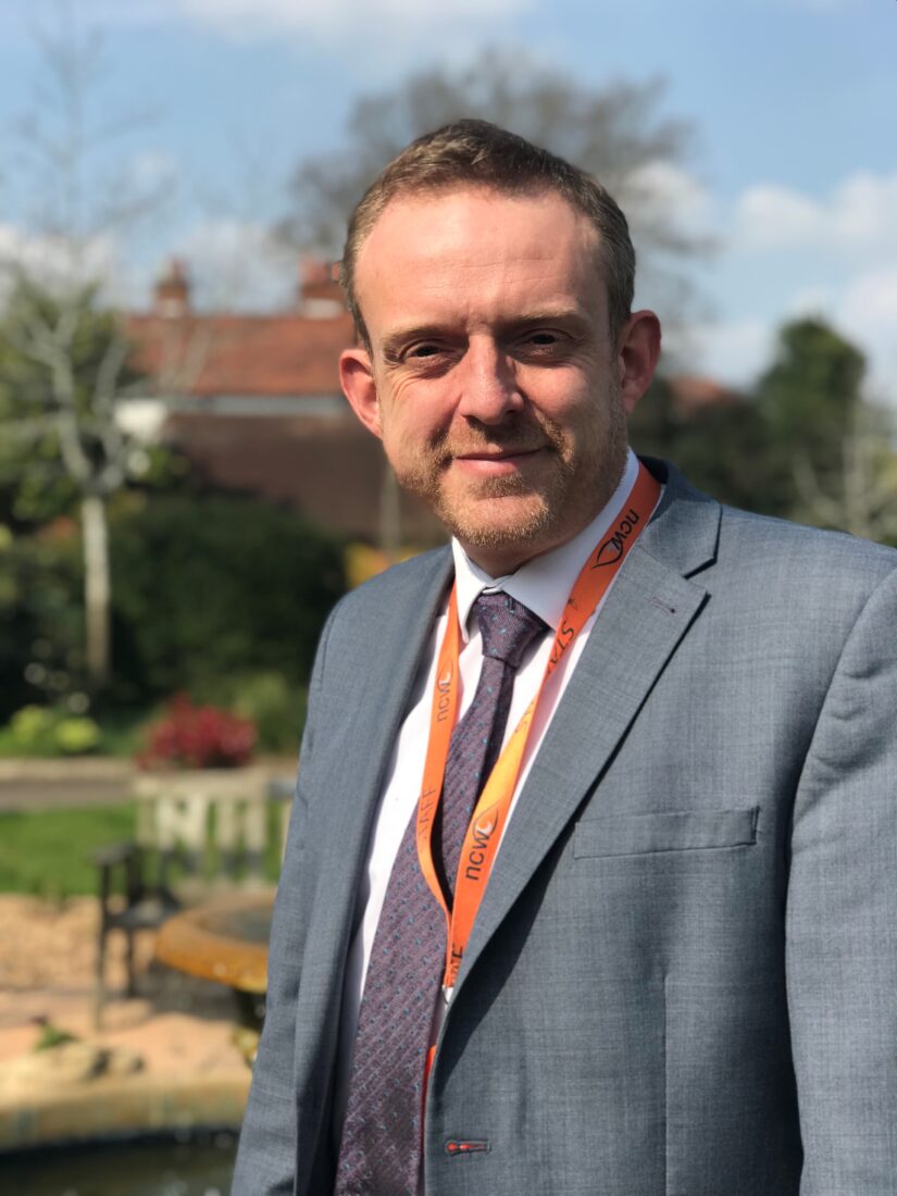 Image of Mr Marnell, smiling at the camera. The fountain is in the background.