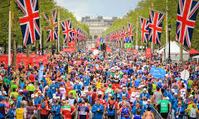 image of a London Marathon. There are lots of people running on Pall Mall. There are Union Jack flags along the avenue.