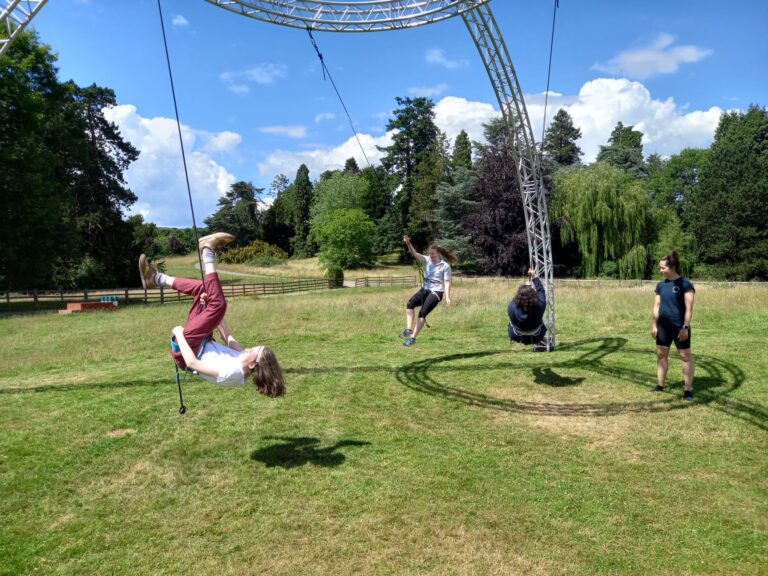 Students are hanging just above the ground in harnesses