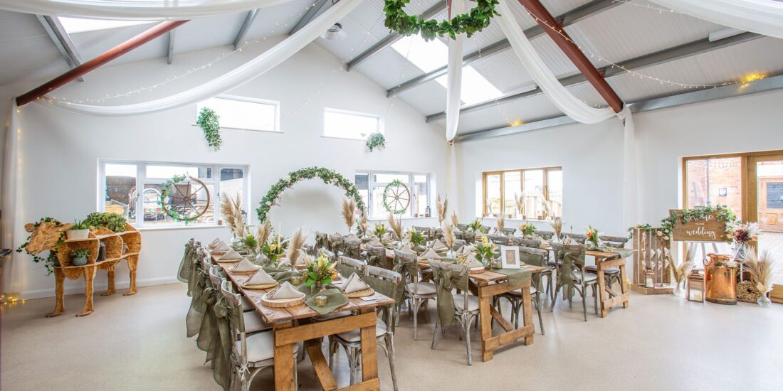 The Churchfields Venue - a large room with tables and chairs decorated with ribbon and foliage