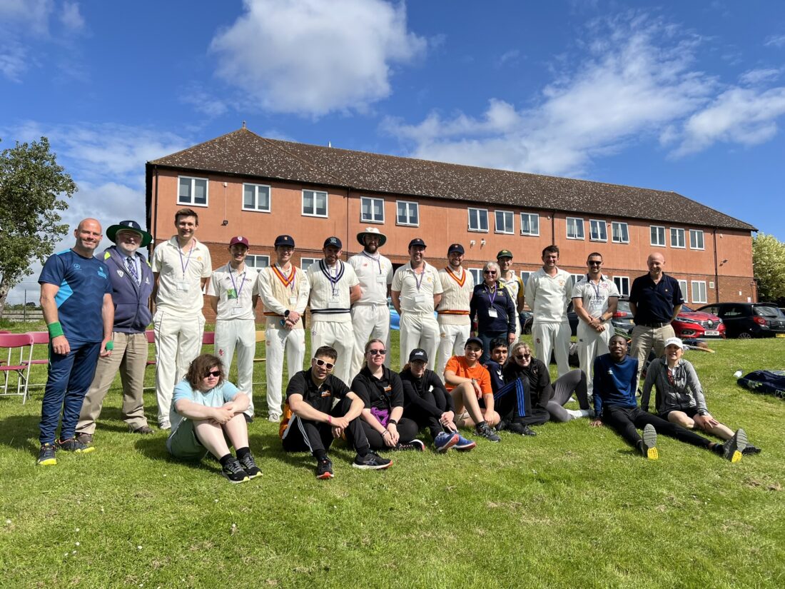 group photo of MCC players, staff and students on the lawn of the sports field all smiling