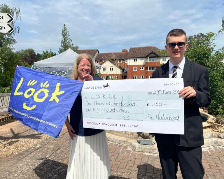 image of Jane from Look UK holding a blue Look UK Flag with Zac holding a giant cheque