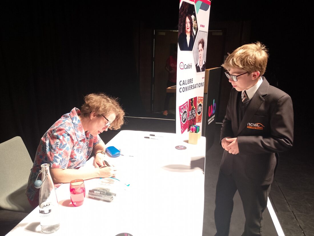 Image of Zaki standing next to a table whilst the author signed their book!