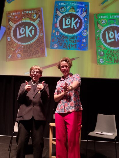 photo of Zaki and the author smiling and giving a thumbs up whilst stood on a stage