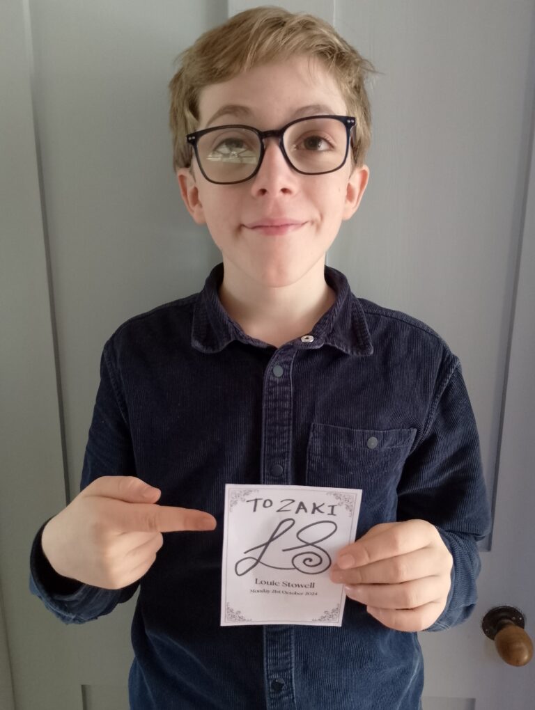 image of Zaki smiling whilst holding his autograph