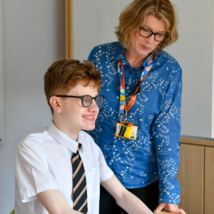 image of a male student reading Braille next to a teacher