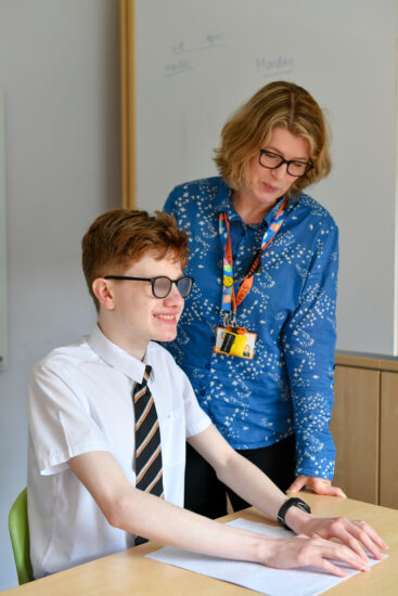 image of a male student reading Braille next to a teacher