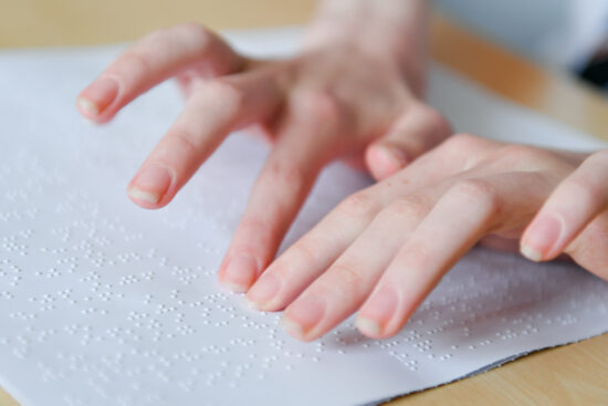 image of a students hands reading printed braille