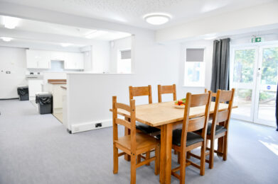 photo of a dinning table and six chairs and the kitchen bays in the foreground