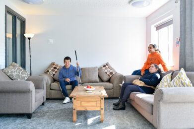 image of three students sat on sofa in the common room area of the accommodation.