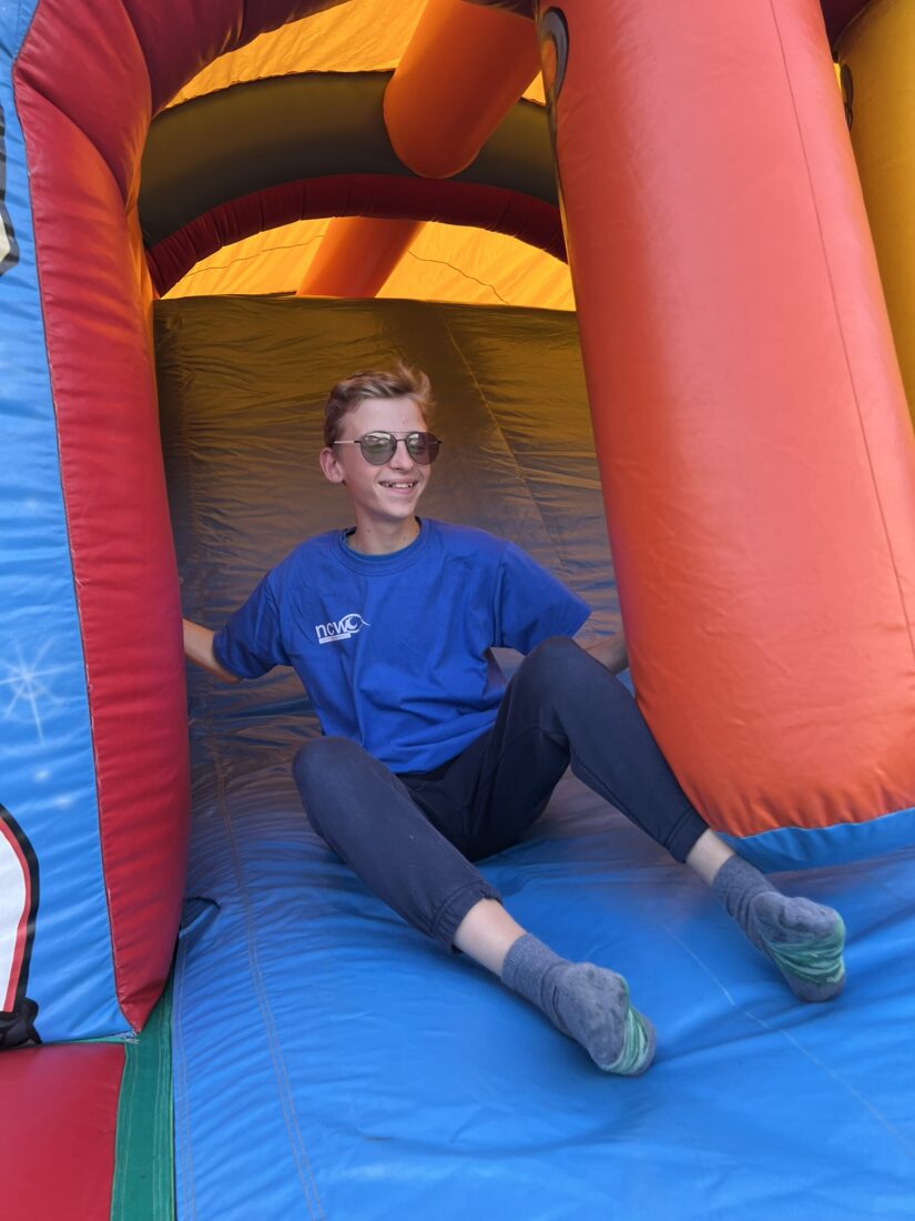 Image shows a young person on a bouncy castle slide