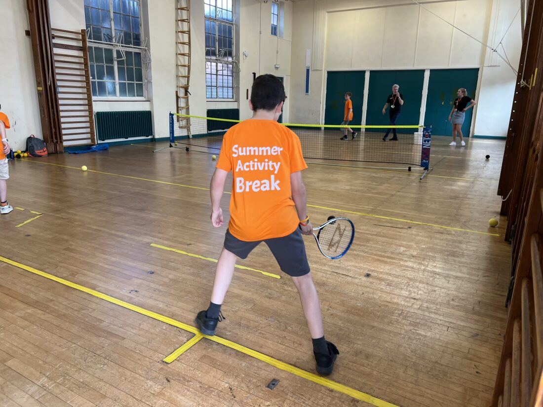 A photo of a young person in an orange t shirt playing tennis