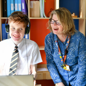 image of a student and teacher laughing whilst looking at a pc