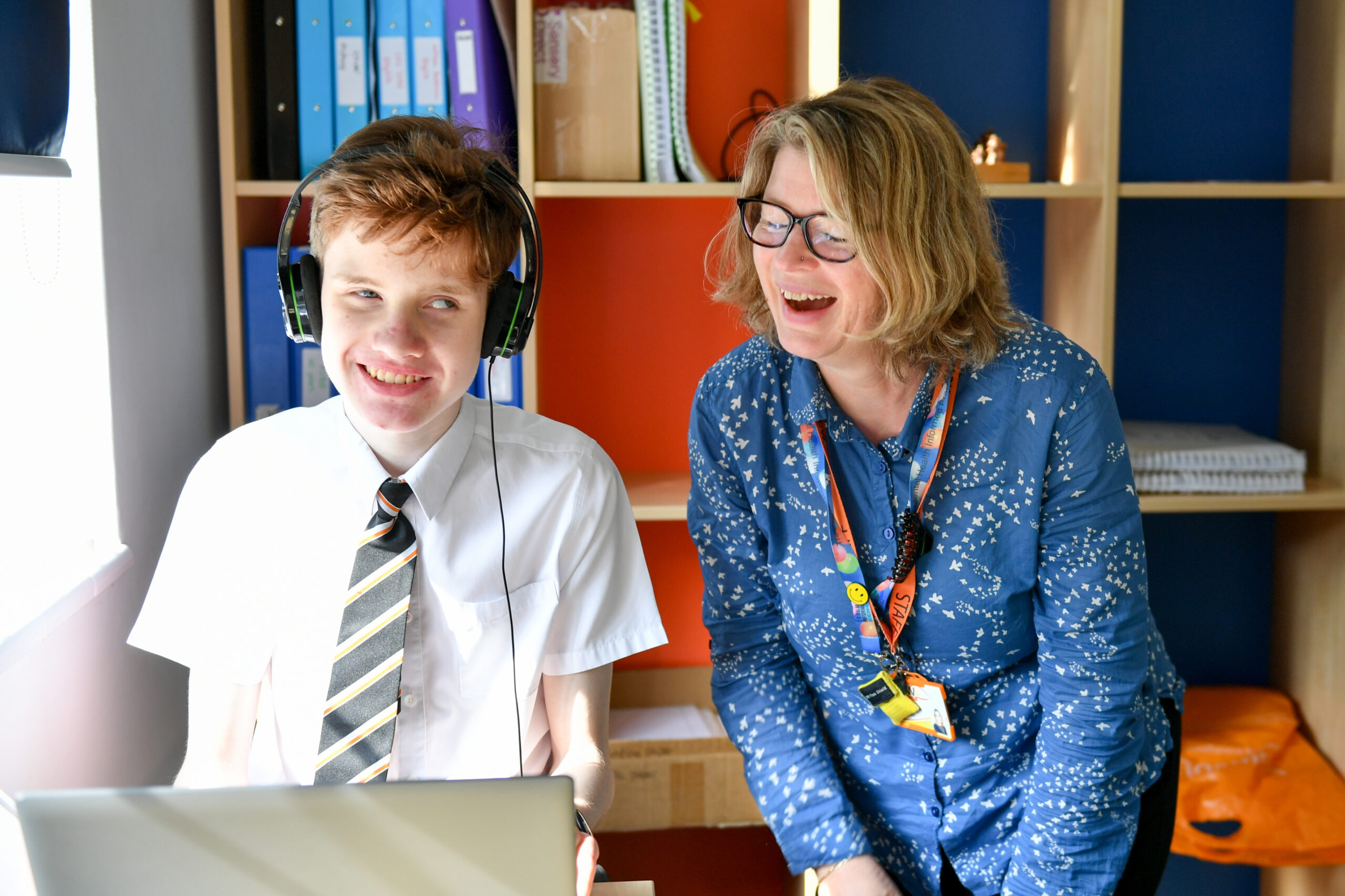 image of a student and teacher laughing whilst looking at a pc