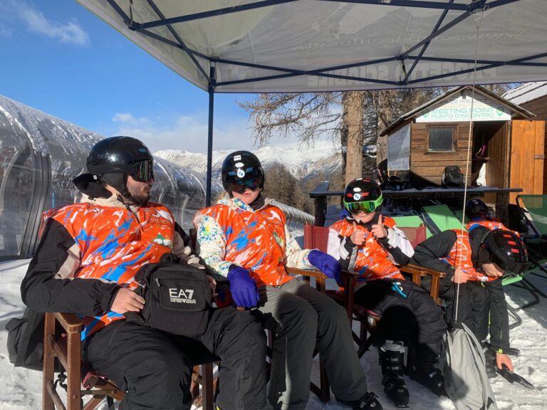 group image of students in ski wear sat down under a gazebo