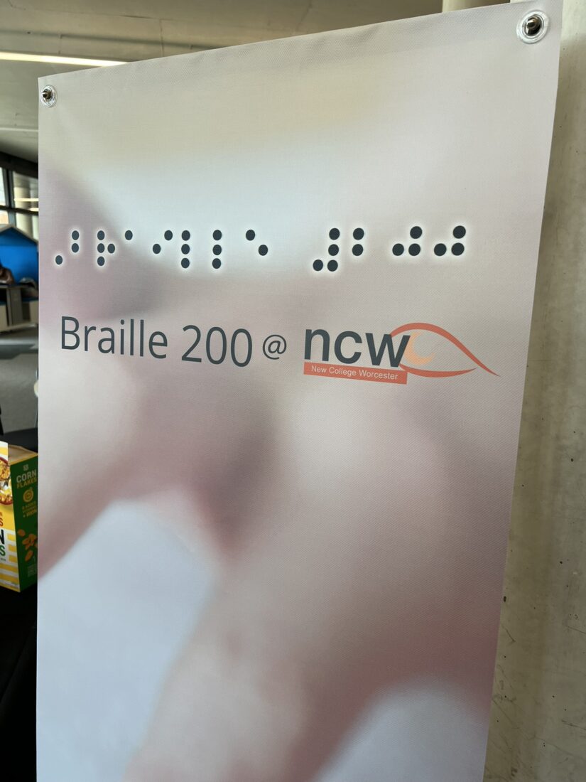 photo or the NCW Braille 200 banner which is a photo of hands reading Braille and the text "Braille 200 at NCW" and in Braille