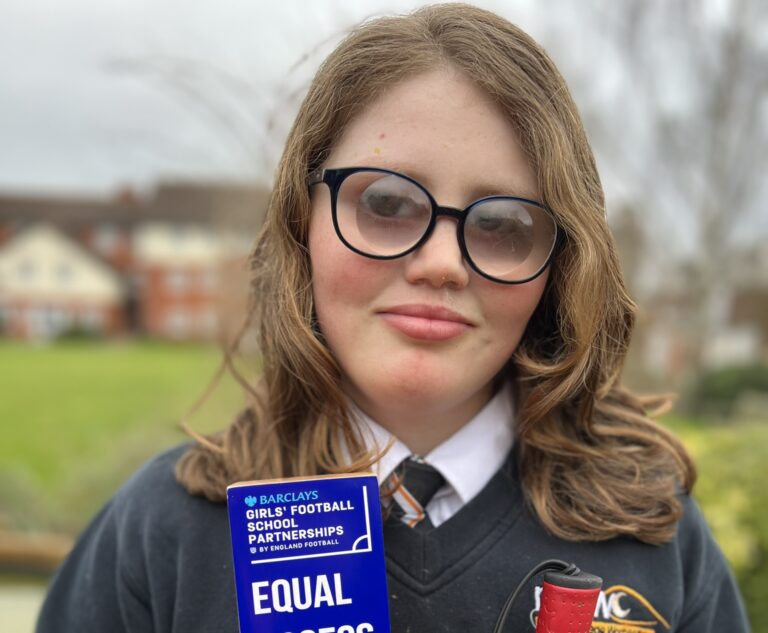 image of an NCW student with a vision impairment smiling at the camera whilst holding an award from Barclays "Equal Access School 24"