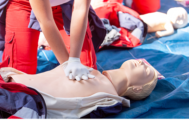 Image shows first aid dummy with hands doing cpr, first aid red cross