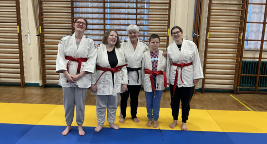 group photo of students in the judo suits and wearing their belts smiling